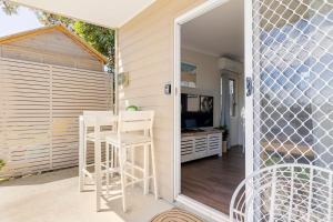a patio with a table and two white stools at Kingscliff Spacious Beach Cottage in Kingscliff