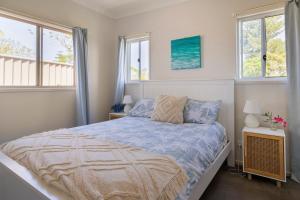 a bedroom with a bed and two windows at Kingscliff Spacious Beach Cottage in Kingscliff