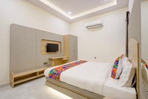 a bedroom with a bed and a tv on a wall at FabHotel RR Inn in Kānpur