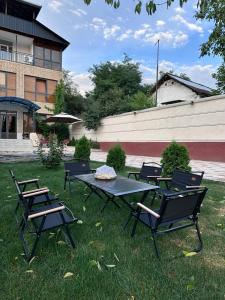 a picnic table and chairs in the grass at River guest house in Osh
