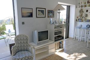 a living room with a tv and a chair at Athanasia Villa in Nerátza