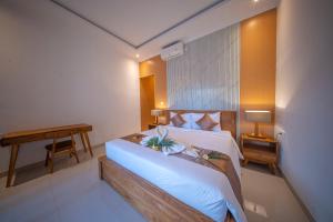 a bedroom with a large white bed and a desk at Eva Guest House in Canggu