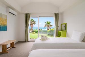 a bedroom with two beds and a window with the ocean at Jeju Turning point Pension in Seogwipo