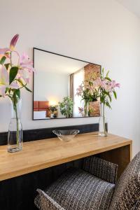 a mirror on top of a wooden table with flowers at Hotel Jazz Market Square Wroclaw in Wrocław
