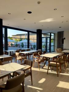 a restaurant with tables and chairs and large windows at Grand Station Hotel in Shkodër