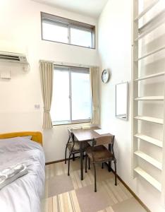 a bedroom with a table and a bed and a window at The Scene Fuchinobe in Sagamihara