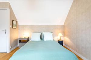 a bedroom with a large blue bed with two white pillows at Une Chambre À Lestriguiou in Plomeur