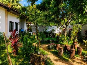 a garden with trees and logs in front of a house at Trio Mango Stay in Arugam Bay