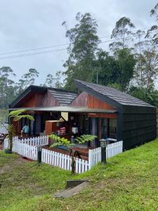 a small house with a white fence in front of it at Cozzy Boemi Chips Pangalengan in Palayangan