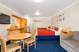 a hotel room with a bed and a table and chairs at Econo Lodge Alabaster Motel Cowra in Cowra