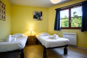 two beds in a room with yellow walls and a window at Chez Romane in Riquewihr