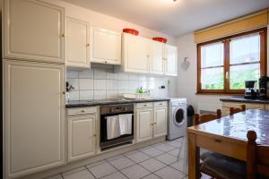 a kitchen with white cabinets and a stove top oven at Chez Romane in Riquewihr