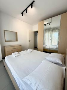 a bedroom with a large white bed and a mirror at Seaview Apartment in Dhërmi