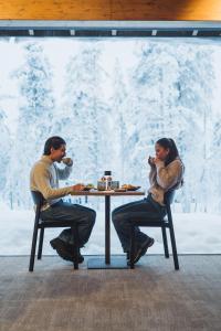 a man and woman sitting at a table eating food at Wilderness Hotel Saariselkä in Saariselka