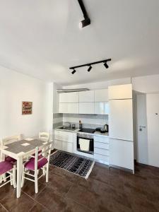a kitchen with white cabinets and a table and chairs at Seaview Apartment in Dhërmi