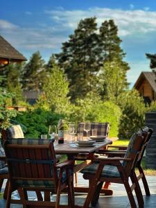 a wooden table with chairs and glasses on a patio at Chata Mila in Veľká Lomnica