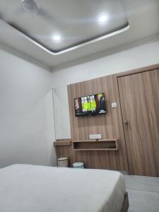 a bedroom with a bed and a tv on a wall at Hotel Namaste Ac Rooms in Vadodara