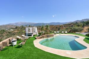 a pool with chairs and a lawn with mountains in the background at El Rincón de Esther in Cómpeta