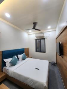 a bedroom with a white bed with a tv on the wall at Hotel Namaste Ac Rooms in Vadodara