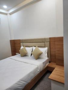 a bedroom with a bed with white sheets and pillows at Hotel Namaste Ac Rooms in Vadodara