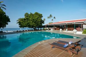 a swimming pool with a bench next to a building at Citrus Hikkaduwa in Hikkaduwa