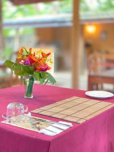 a vase of flowers on a table with a pink table cloth at Raniya Villa in Bentota