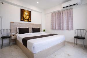 a bedroom with a large bed and two chairs at Hotel Shubh Bodhi in Bodh Gaya