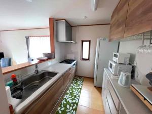 a kitchen with a sink and a refrigerator at すずめのとまりぎ in Nasu
