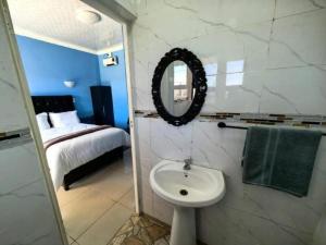 a bathroom with a sink and a mirror and a bed at Zamdu Lodge in Nkandla