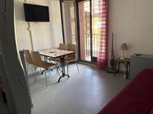 a room with a table and chairs and a television at Centre village, proche toutes commodités in Les Angles