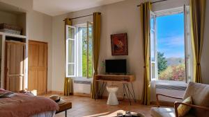 a bedroom with a bed and a desk with a television at La Cour des sens, domaine d'hôtes- Spa piscine chauffée in Lagnes