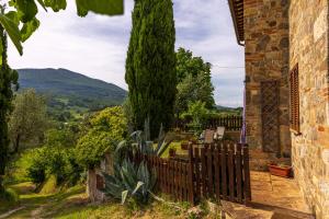 a fence in front of a house with a tree at Casa Vecciano in Cetona