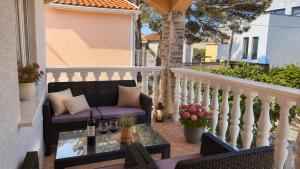 a balcony with a couch and a table with wine bottles at Apartmani Catakovic in Vir