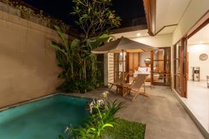 an indoor pool with an umbrella next to a house at Coco Luxury Villas in Ubud