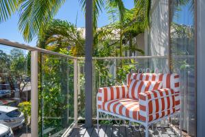 a balcony with two chairs and palm trees at Riverside Retreat, Noosaville in Noosaville