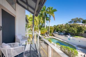 a balcony with a view of a swimming pool and palm trees at Riverside Retreat, Noosaville in Noosaville +11 photos