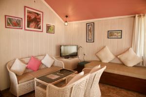 a living room with a couch and a tv at Magpie Retreat in Bhīm Tāl
