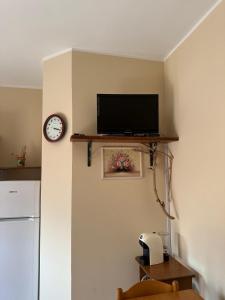 a living room with a television and a clock on a wall at Casa Le Araucarie in Mascali