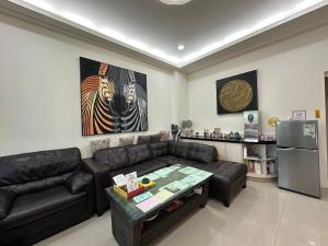 a living room with a black couch and a refrigerator at Yixiangjing Guesthouse in Zhushan