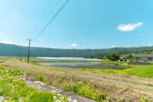 a dirt road next to a river with a body of water at AoAsoVilla in Aso