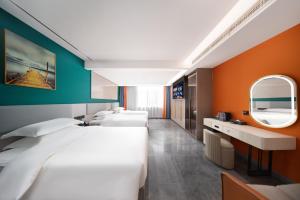 a hotel room with three beds and a mirror at 义乌君威酒店 in Yiwu