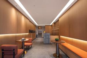 a waiting room with orange chairs and tables at 义乌君威酒店 in Yiwu