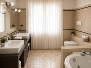 a bathroom with two sinks and a tub and a toilet at Sunshine Luxury Apartment - spacious house - Lake View - Pool in Padenghe sul Garda +12 photos