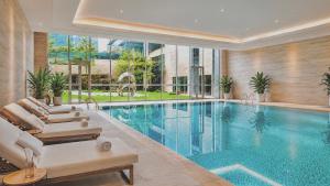 a swimming pool with two lounge chairs next to a pool at Radisson Hotel, Beijing DaXing Airport in Beijing