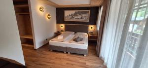 a bedroom with a bed and a large window at Garni Hotel Residence Diamant in San Vigilio Di Marebbe +43 photos
