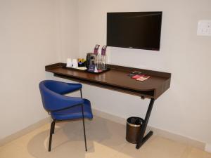 a desk with a blue chair and a television at Surendra Landmark By Spree Hotels Bhopal in Bhopal