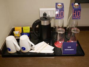 a tray with a coffee maker and cups on a table at Surendra Landmark By Spree Hotels Bhopal in Bhopal