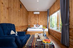a bedroom with a bed and a blue chair and a table at Catcat Garden House in Sapa