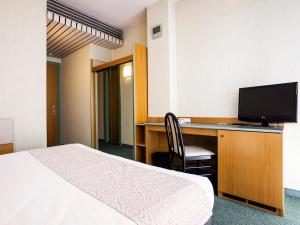 a hotel room with a bed, desk and television at Best Western Hotel Residence Italia in Quartu SantʼElena