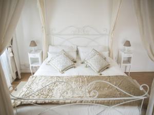 ein weißes Schlafzimmer mit einem weißen Bett und Kissen in der Unterkunft Tisserand Boutique & Apartment in Lido di Ostia